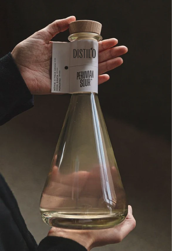 deux mais qui tiennent une bouteille transparante raffiner avec une étiquette marquer distil'o