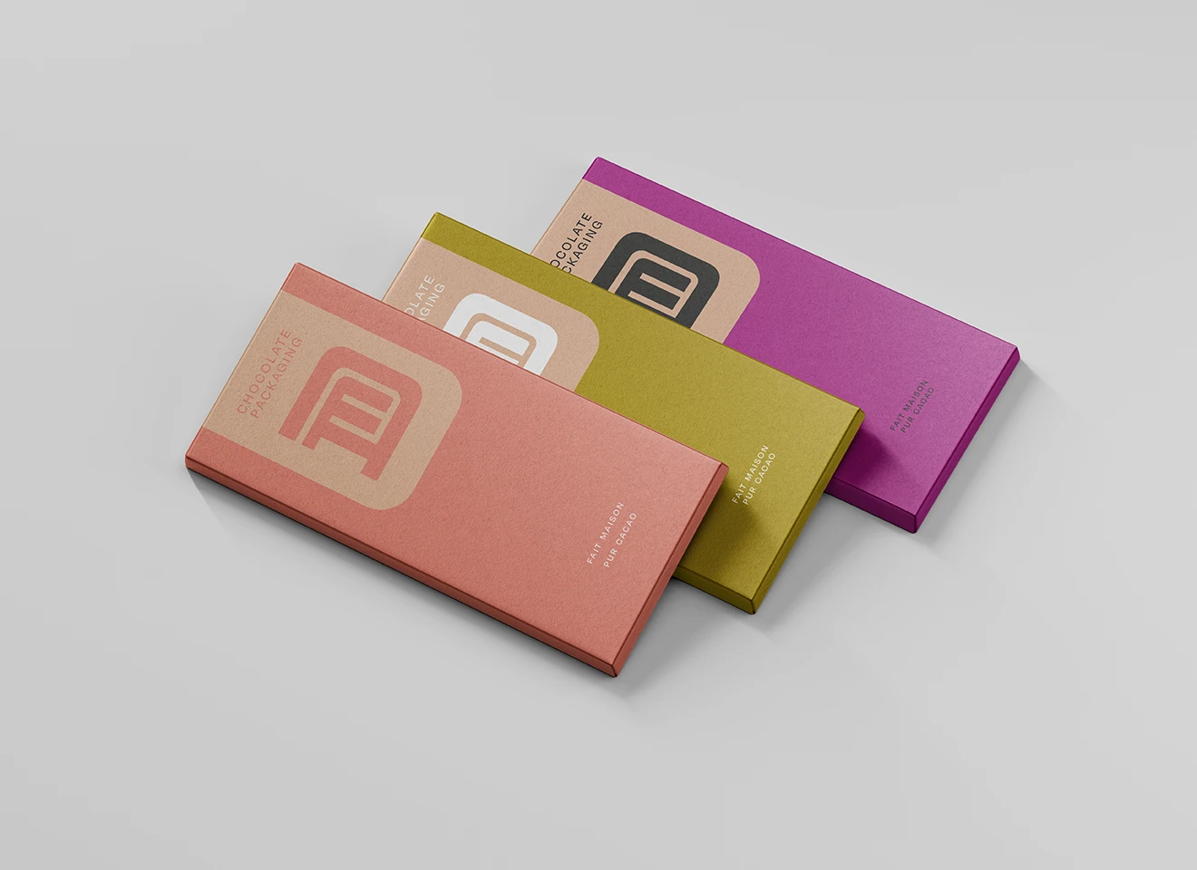Trois tablette de chocolat avec le logo D et M, une corail, une verte pistache, et l'autre violette.