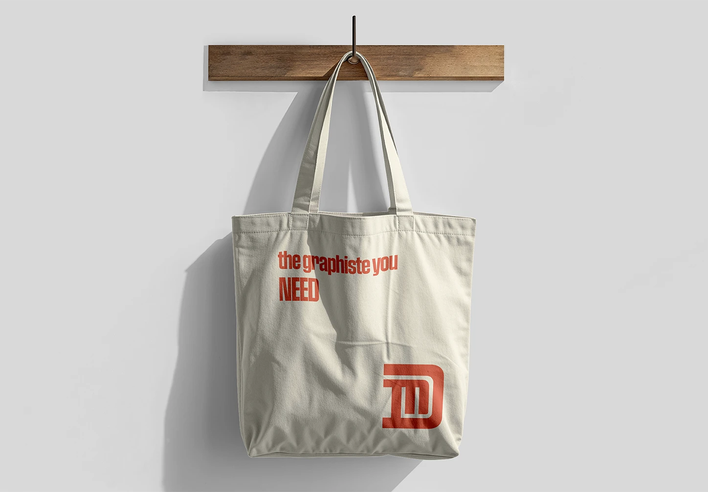 Tote bag plan avec une écriture 'the graphiste you need" et le logo D et M